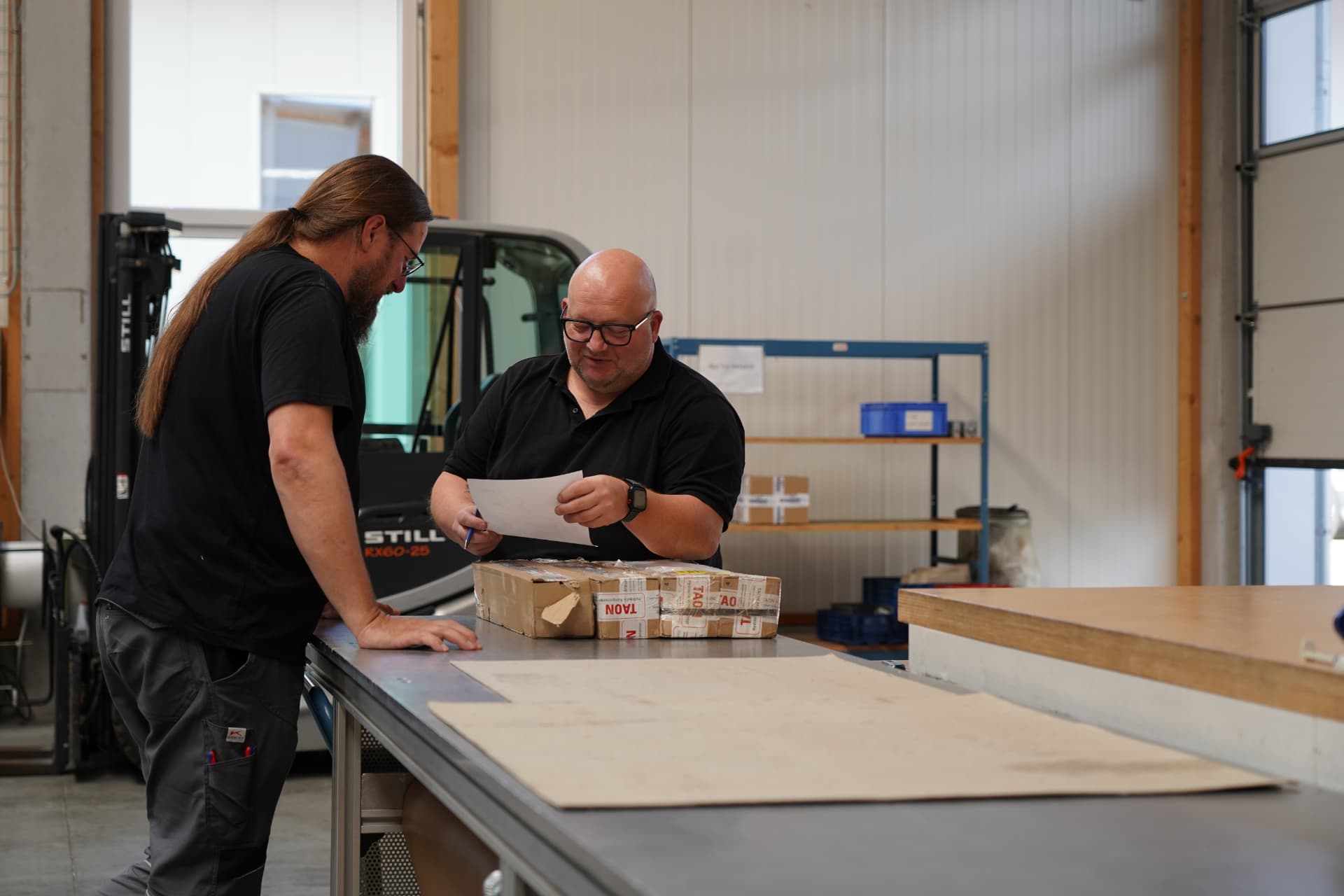 Zwei Mitarbeiter besprechen eine technische Zeichnung in der Montagehalle